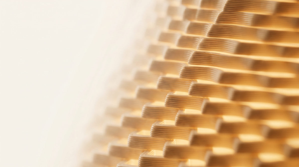 Close-up of a 3D printed shade's layered ridges, backlit so each print line glows amber.